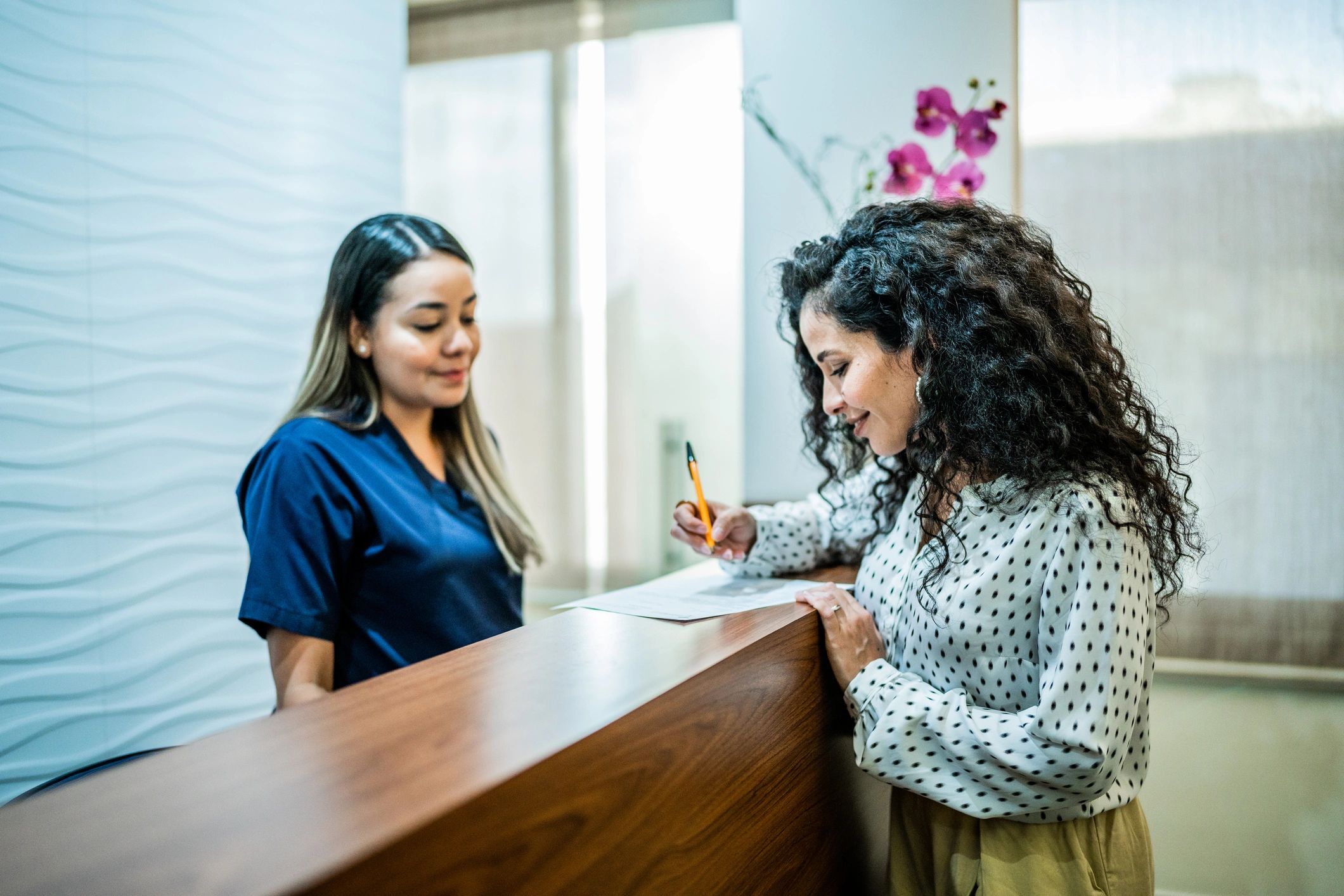 Patient speaking with receptionist at a dental clinic front desk
