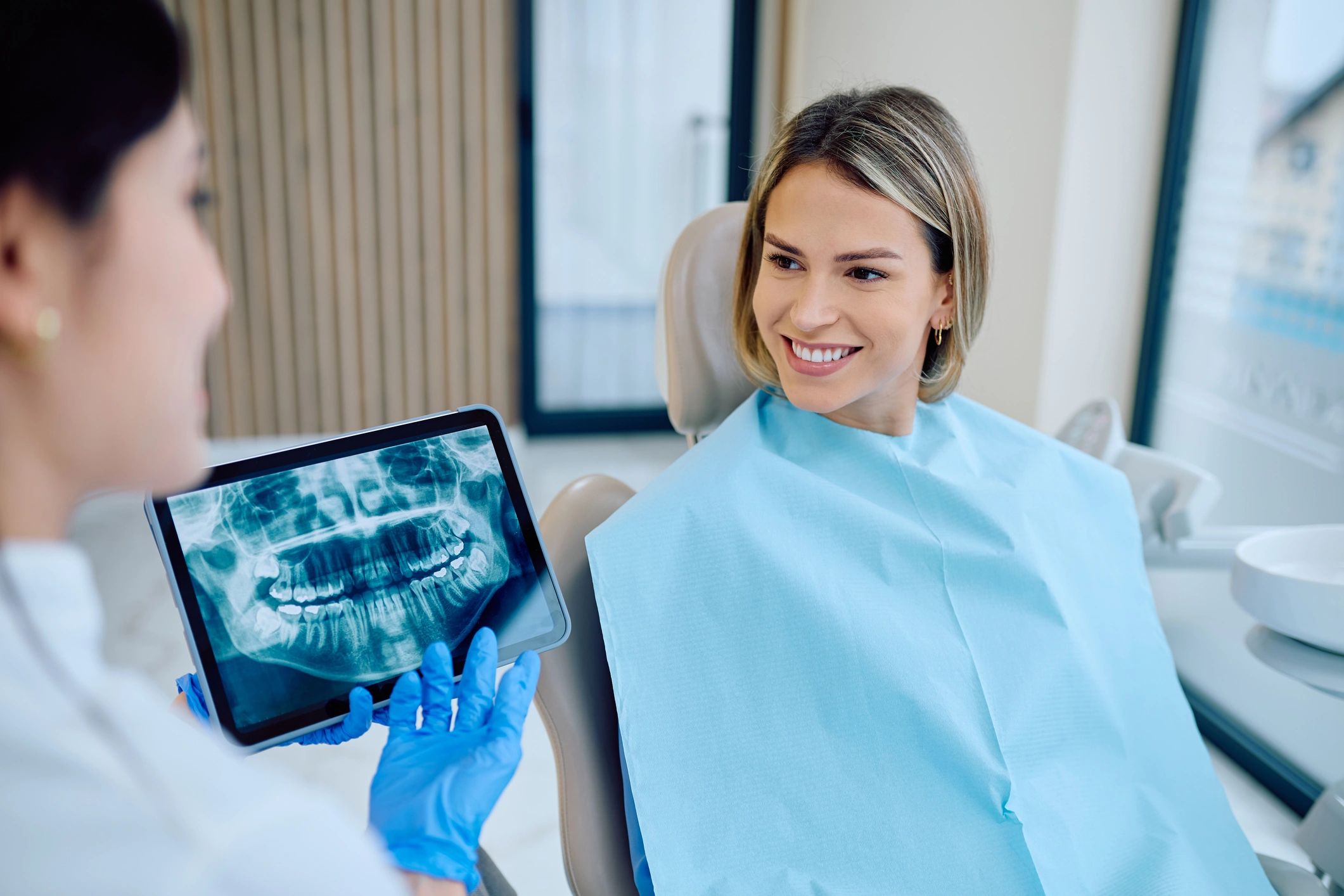 Dentist explaining treatment options to a smiling patient in a dental clinic