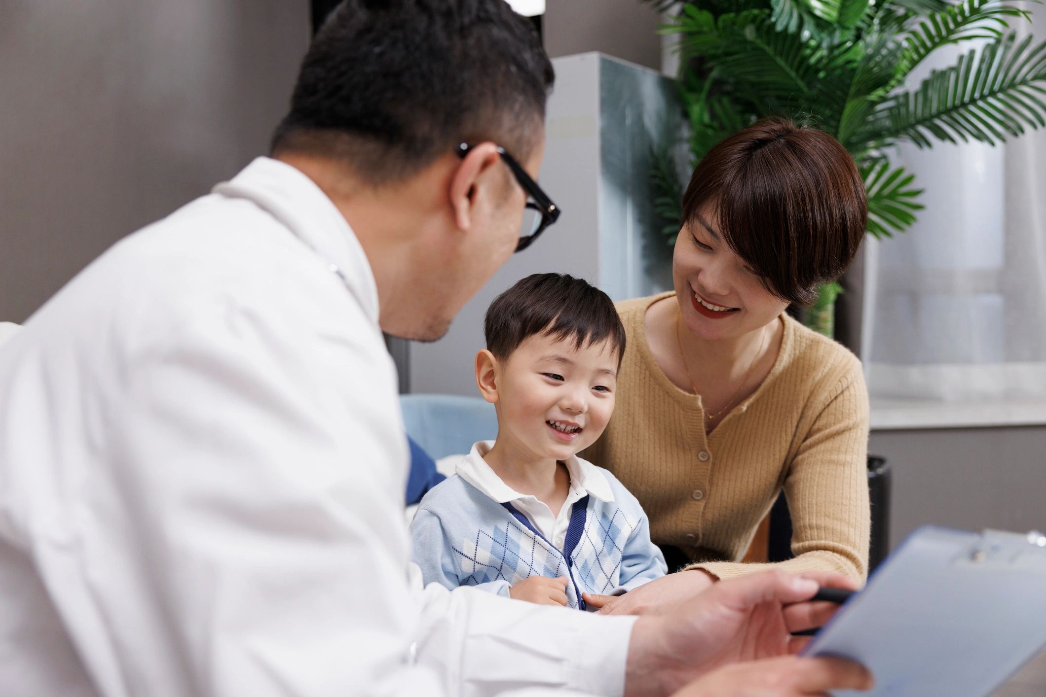 Parent and child speaking with a healthcare professional during a consultation
